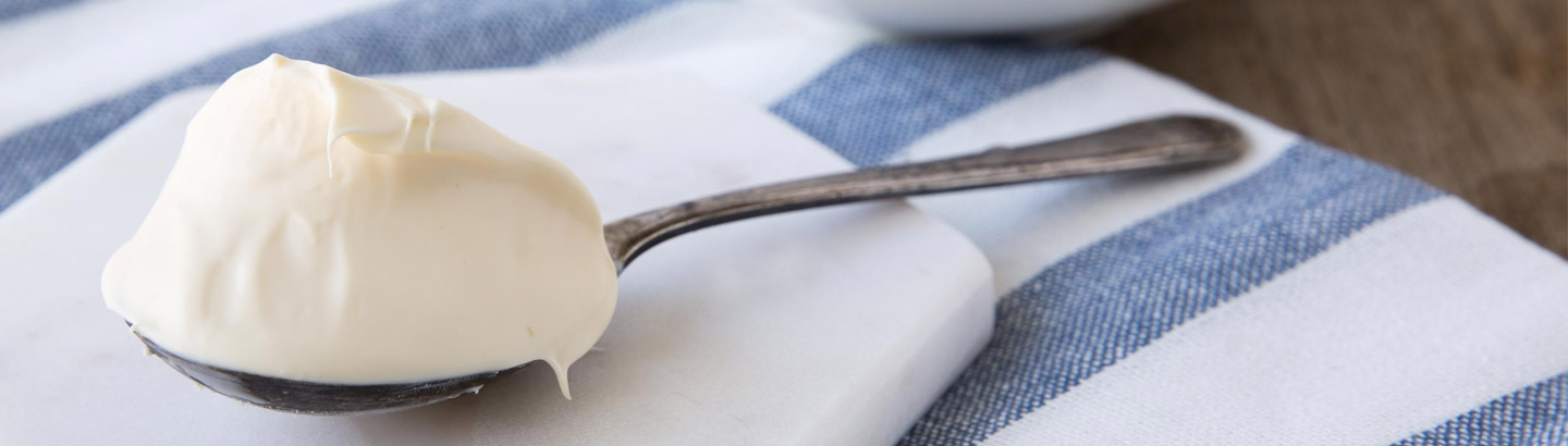 A picture of a generous dollop of cream, served on a silver spoon. 