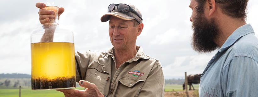 Dairy farmer looking at asparagopsis in jar